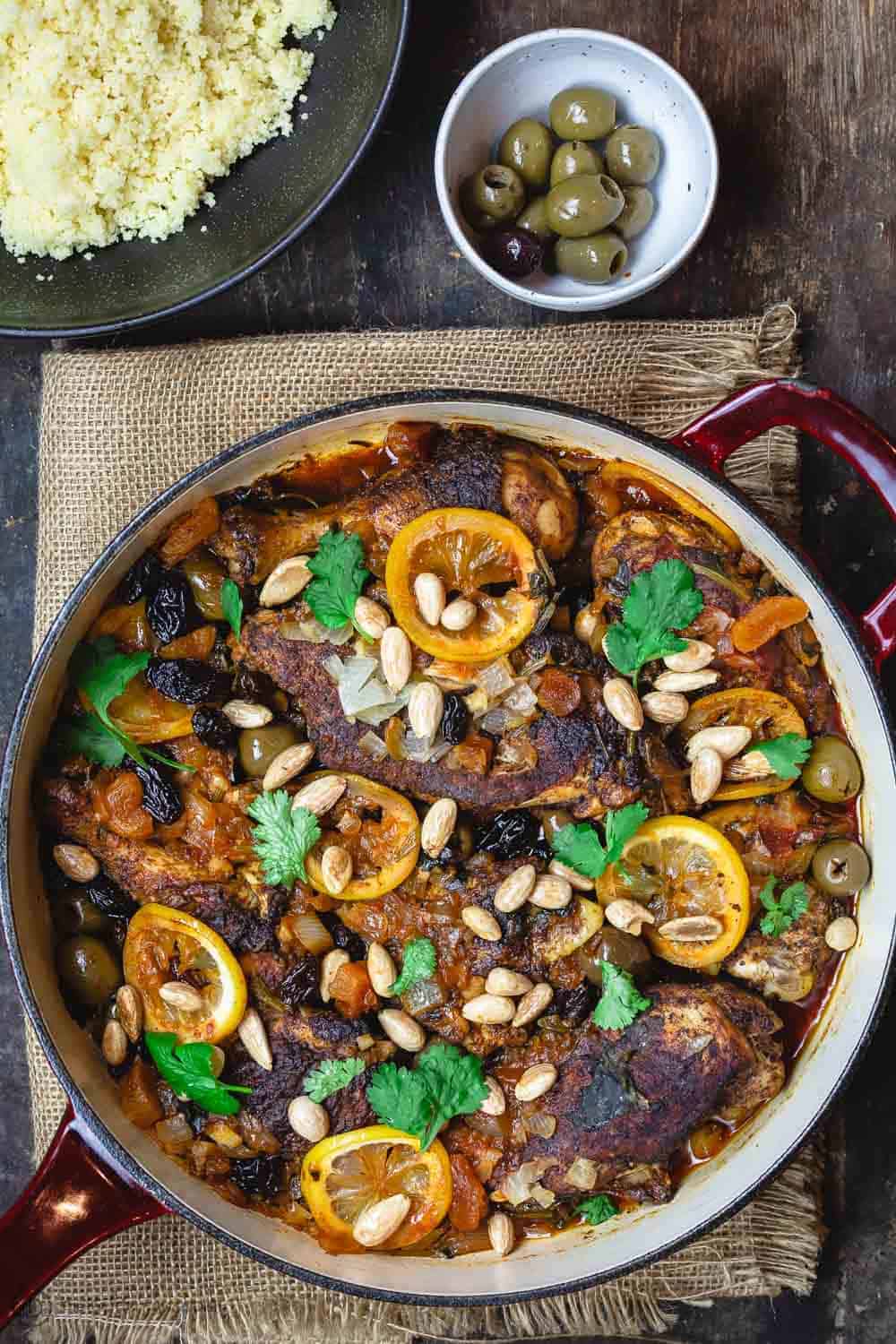 Moroccan chicken with lemons, olives, and dried fruit. Garnished with fresh cilantro and toasted almonds and served with couscous and more olives to the side