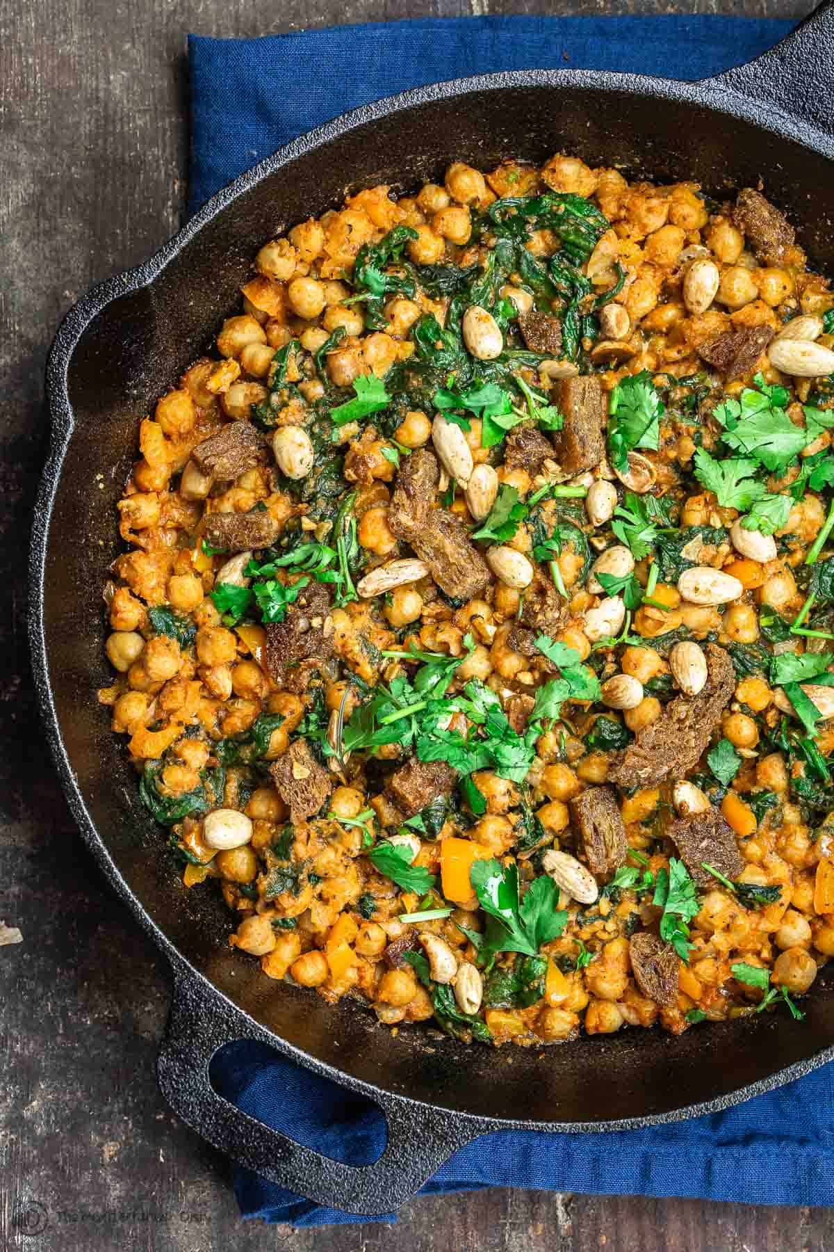 Finished skillet of Chickpea Stew with a garnish of almonds and cilantro