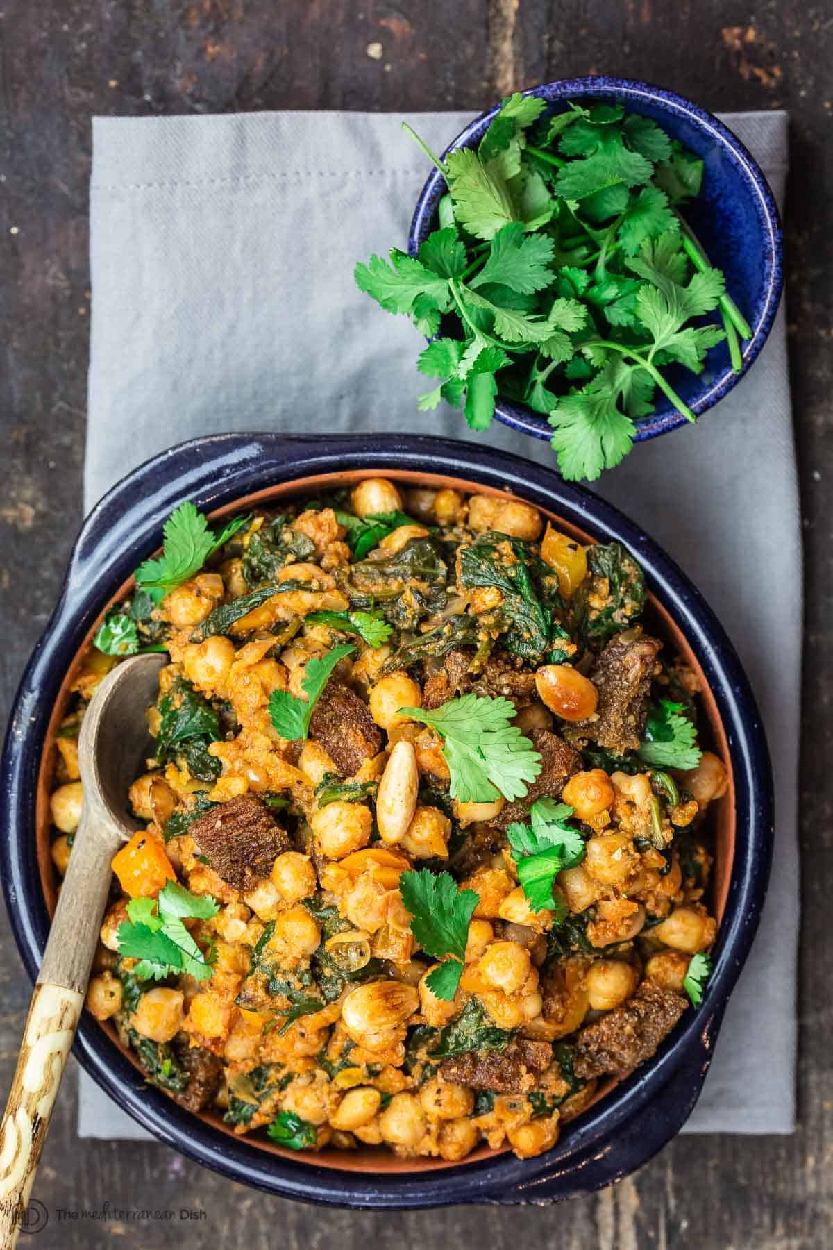 Chickpea Stew Garnished with Cilantro. More cilantro in a small bowl on the side