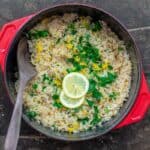 Greek lemon rice in pot cooking pot, garnished with fresh parsley, dill and lemon slices