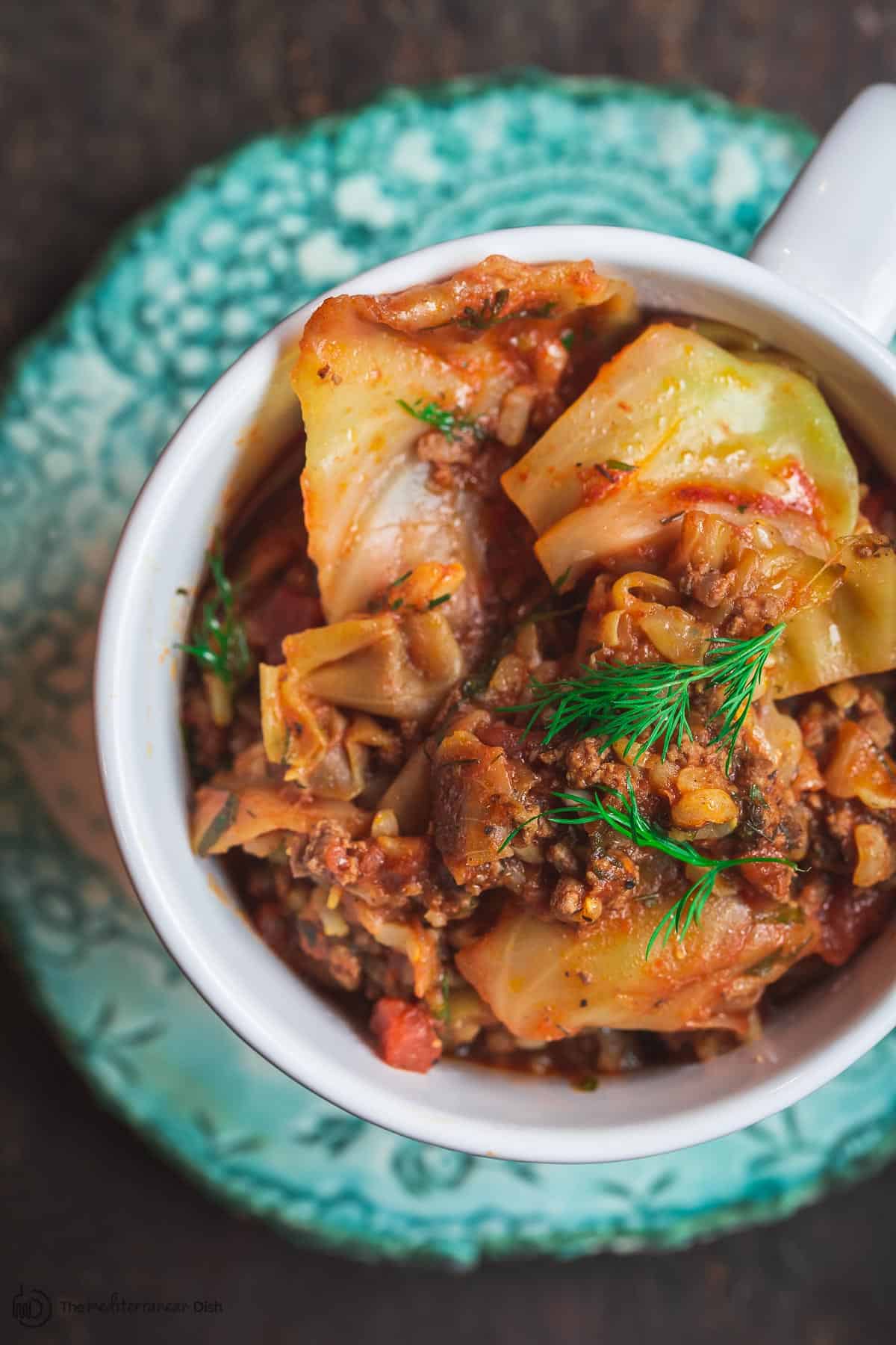 Mediterranean-Style Unstuffed Cabbage Rolls served in bowl with drizzle of olive oil and more fresh herbs on top