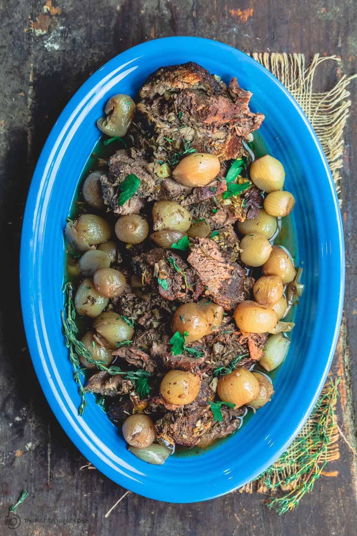 Greek Boneless Leg of Lamb Served on Platter atop a bed of cooked pearl onions