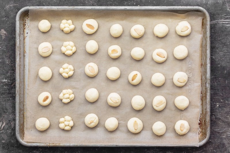 Butter cookie dough formed into small bite-sized pieces and assembled on baking sheet that's lined with parchment paper. Ready for baking.
