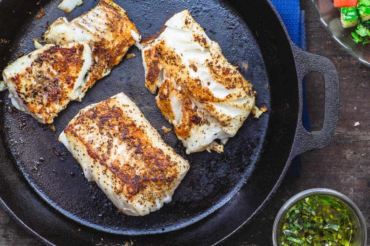 Grilled cod in skillet with a side of lemon basil sauce