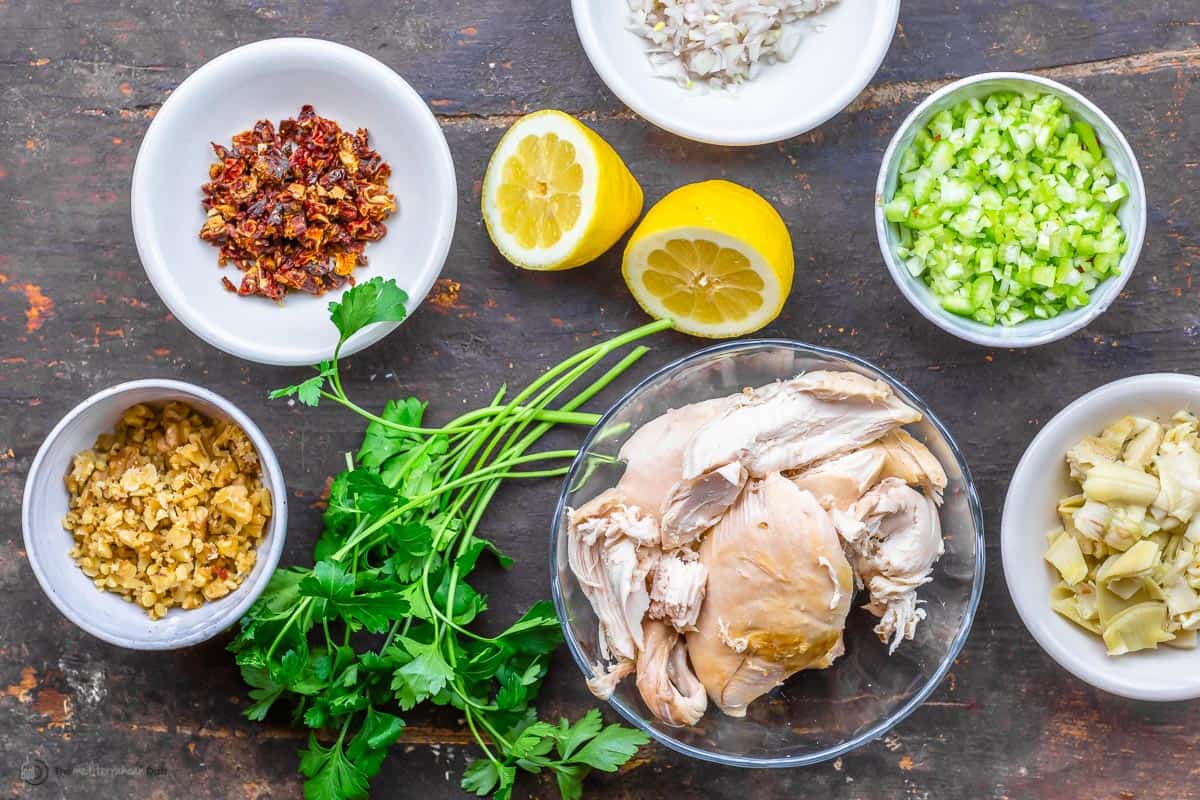 chicken salad ingredients including chicken, celery, lemon, walnuts, fresh herbs, sundried tomatoes