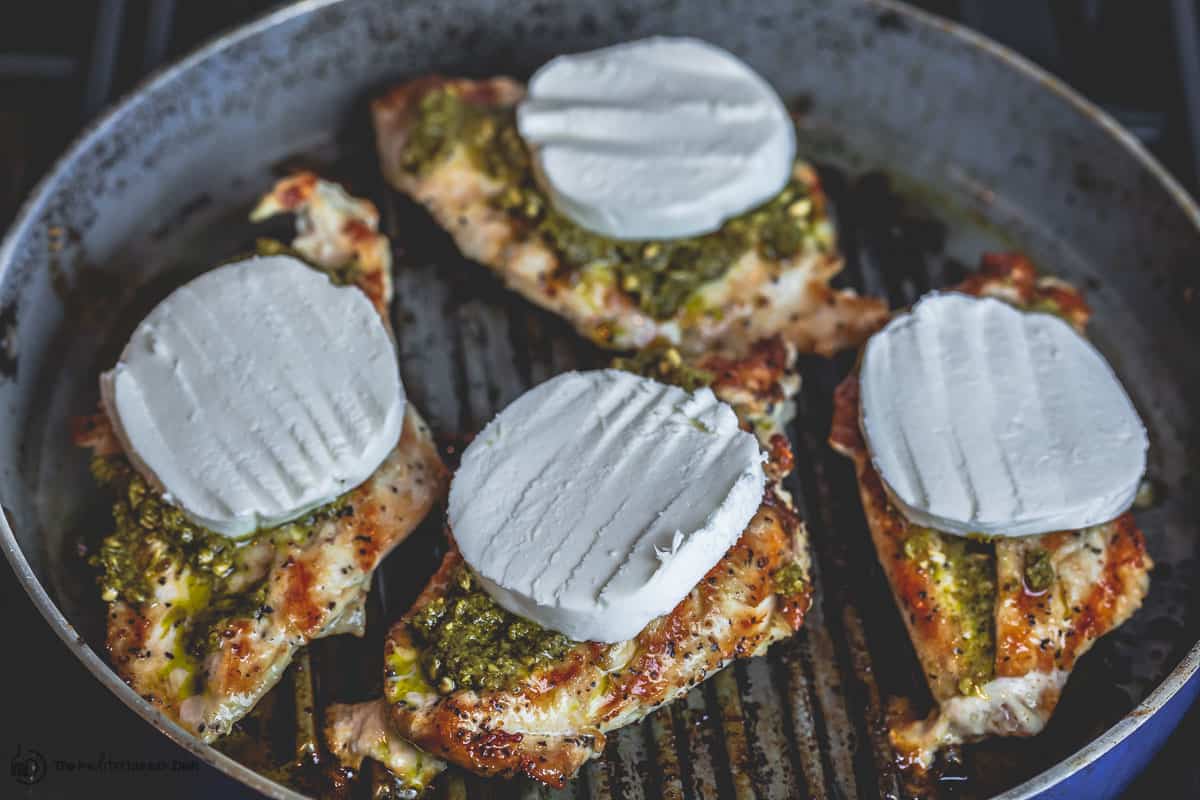 Grilled chicken breasts now topped with basil pesto and fresh mozzarella