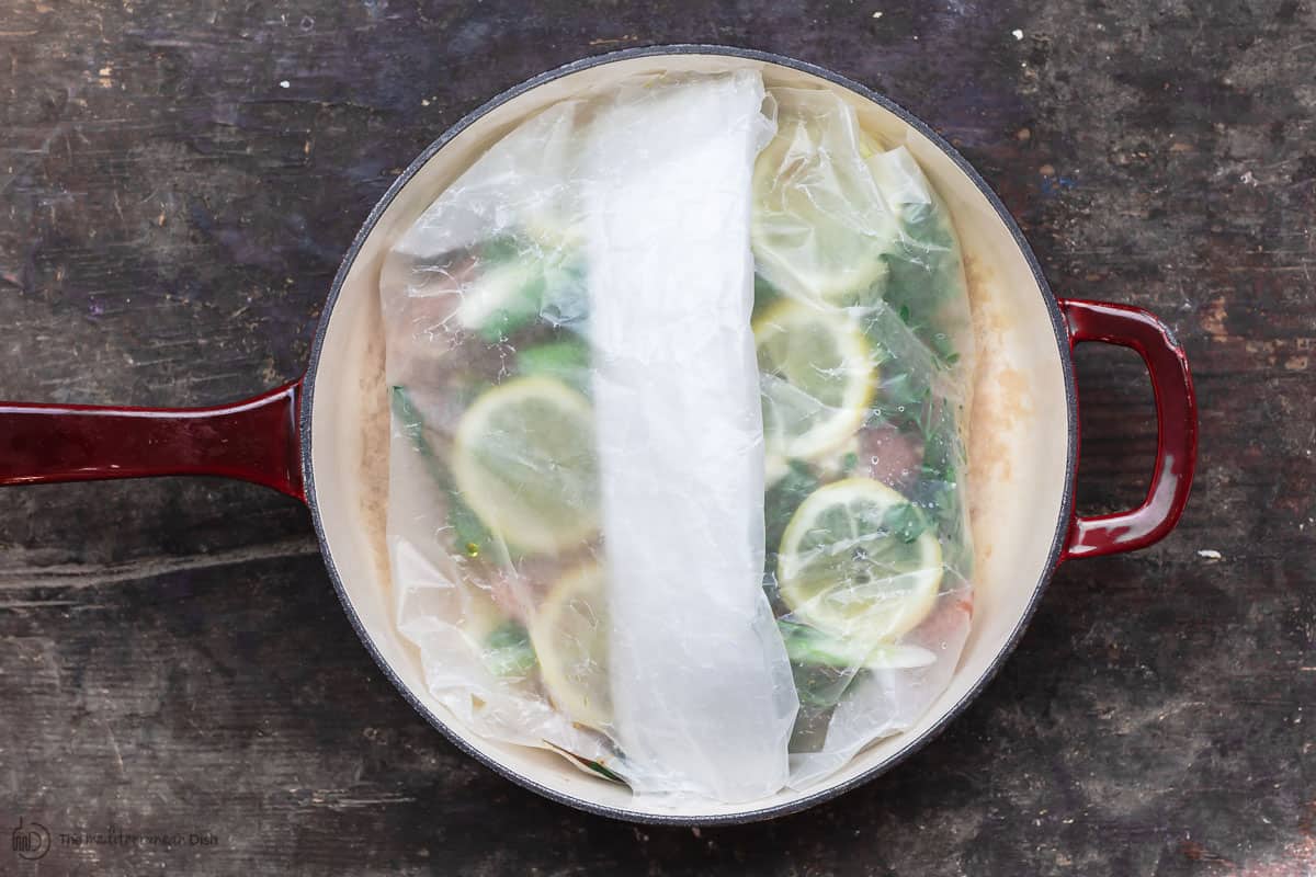 Parchment paper is folded to create a pouch for steamed salmon