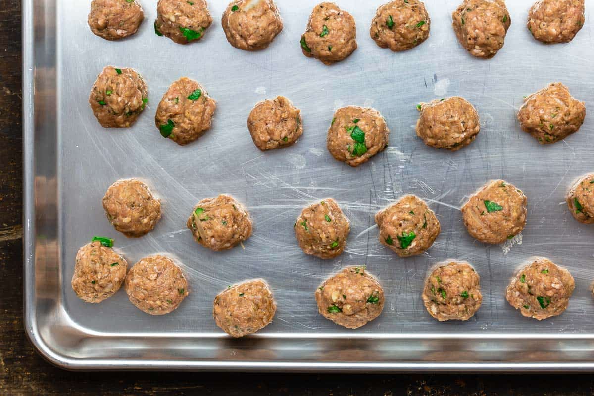 Meatballs arranged on tray to cool in fridge before cooking