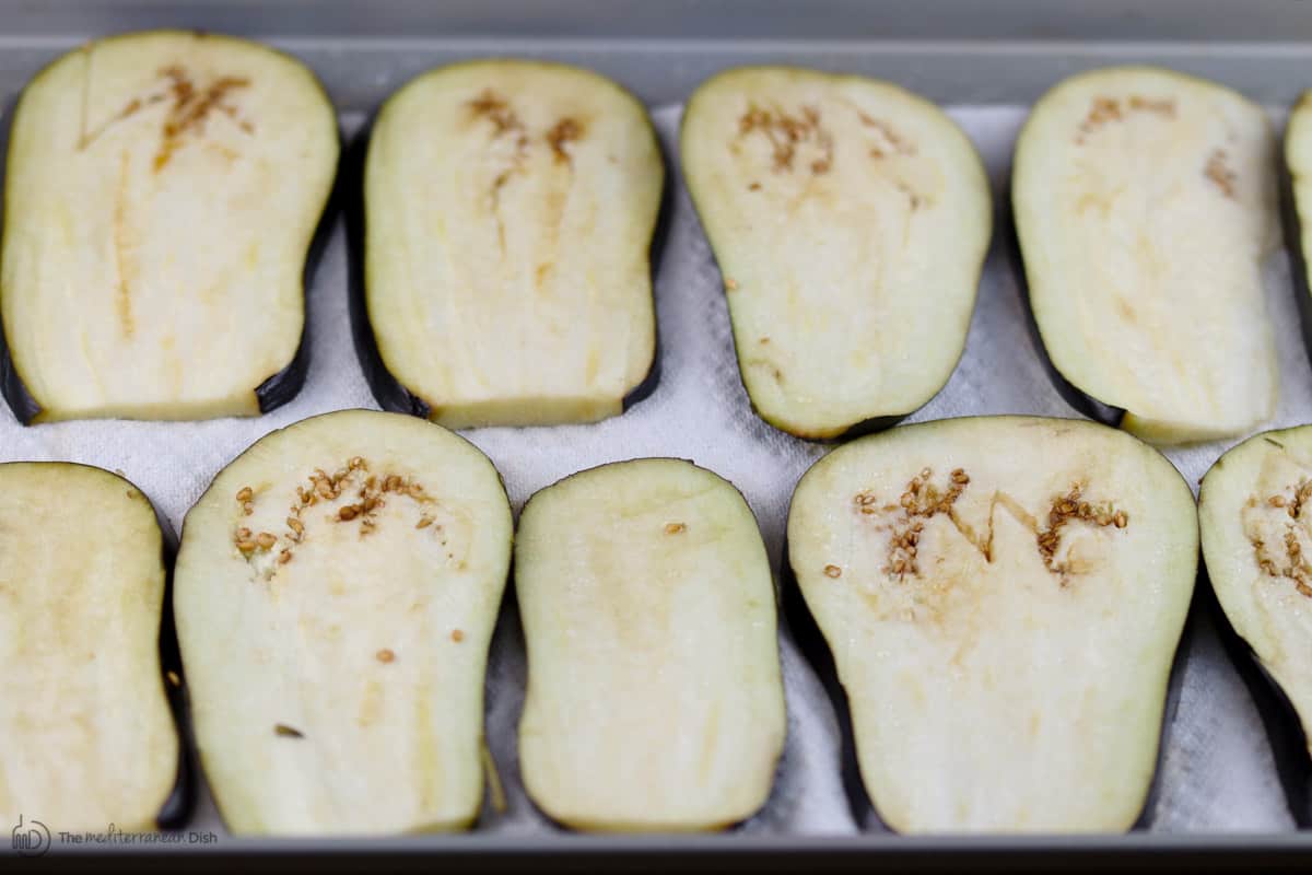 Slices of fresh eggplant laid on top of tray and salted