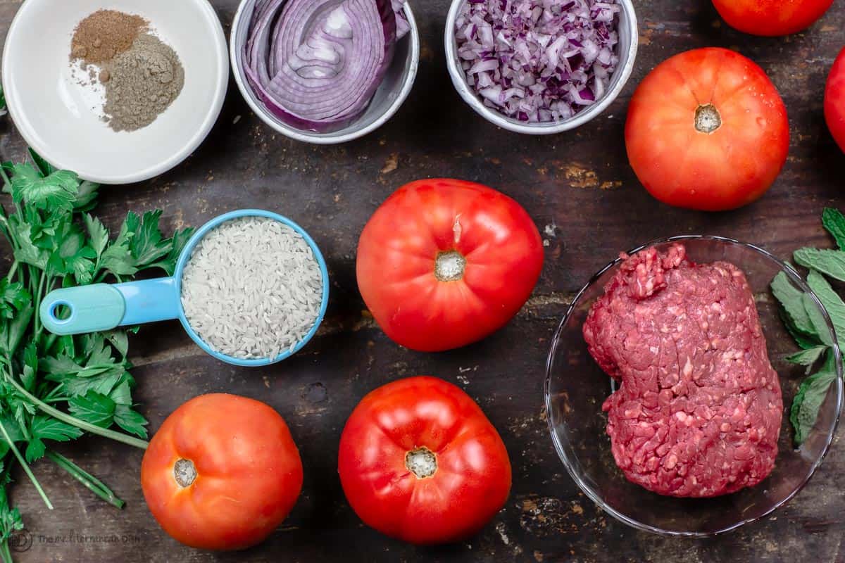 Ingredients for Greek stuffed tomatoes. Rice, beef, tomatoes, aromatics and herbs