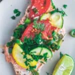 Oven baked salmon served on a plate with vegetables and parsley