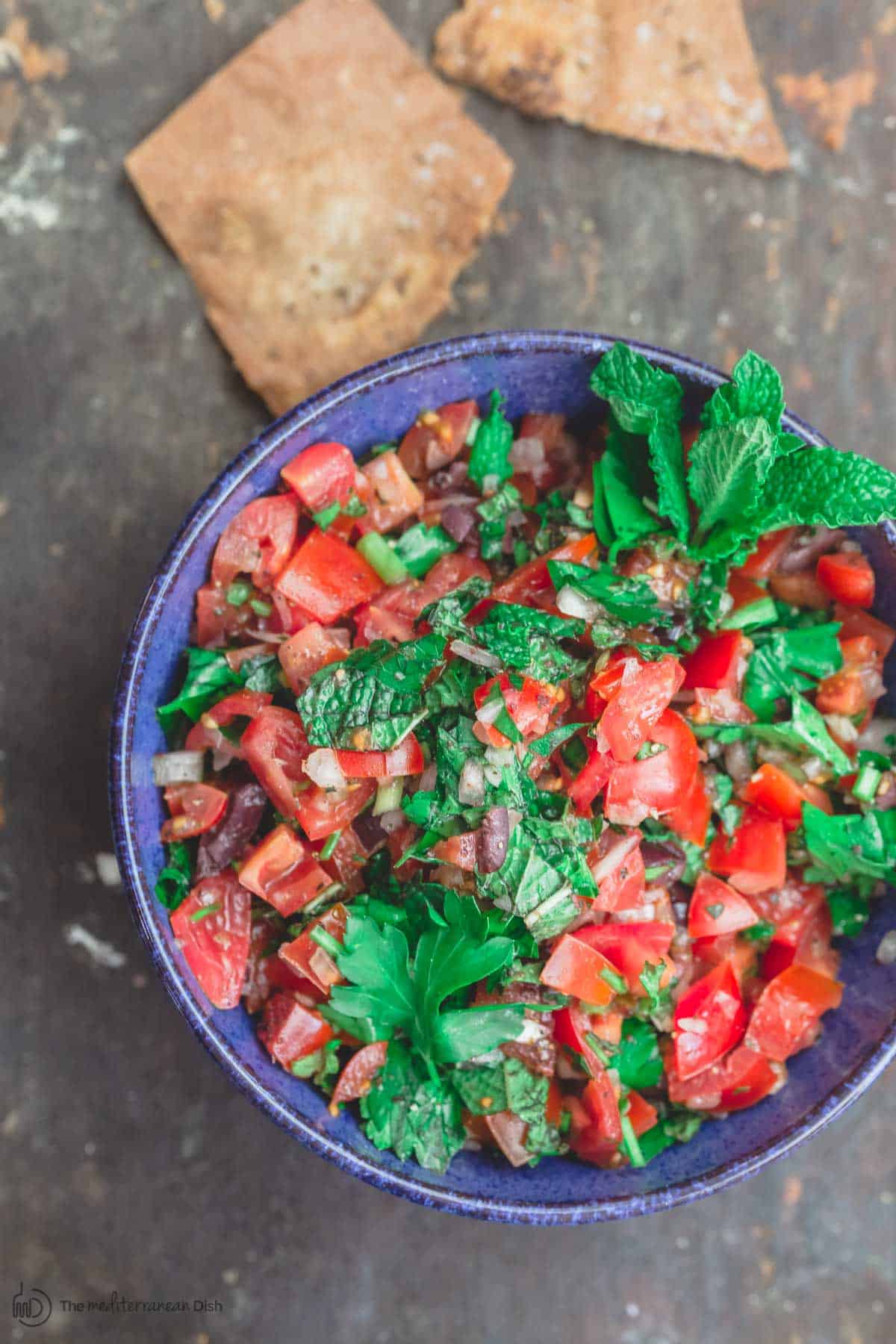 Mediterranean fresh tomato salsa served in a blue bowl, with pita chips
