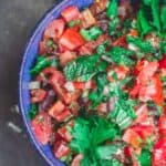 Homemade salsa with chopped tomatoes, onions, parsley and mint, served in a blue bowl