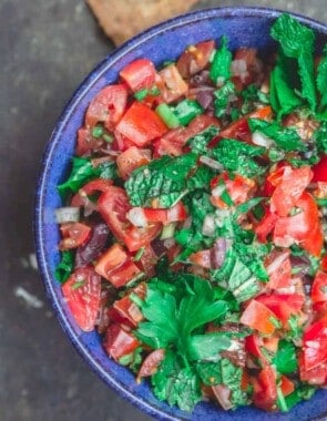 Homemade salsa with chopped tomatoes, onions, parsley and mint, served in a blue bowl