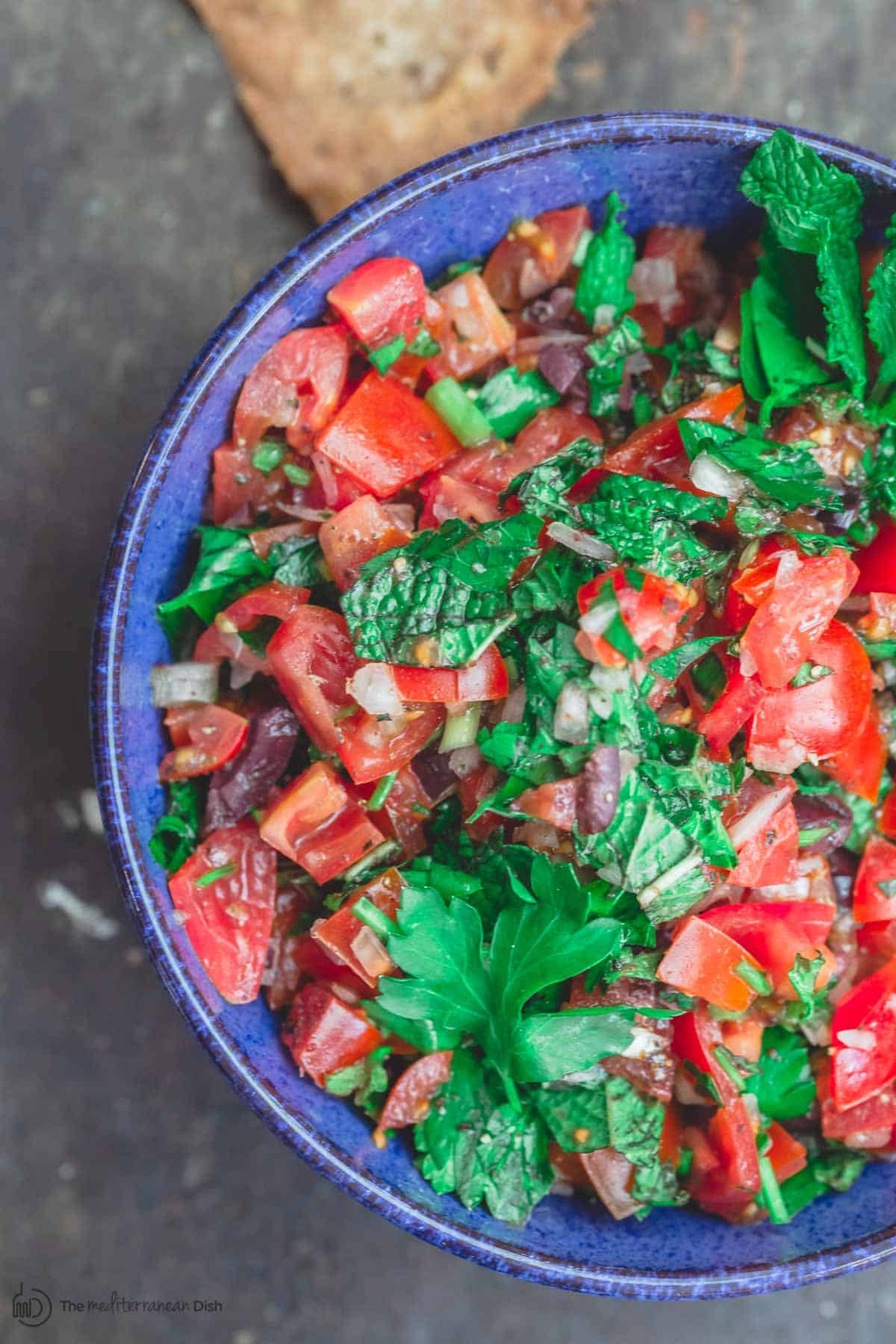 Homemade salsa with chopped tomatoes, onions, parsley and mint, served in a blue bowl