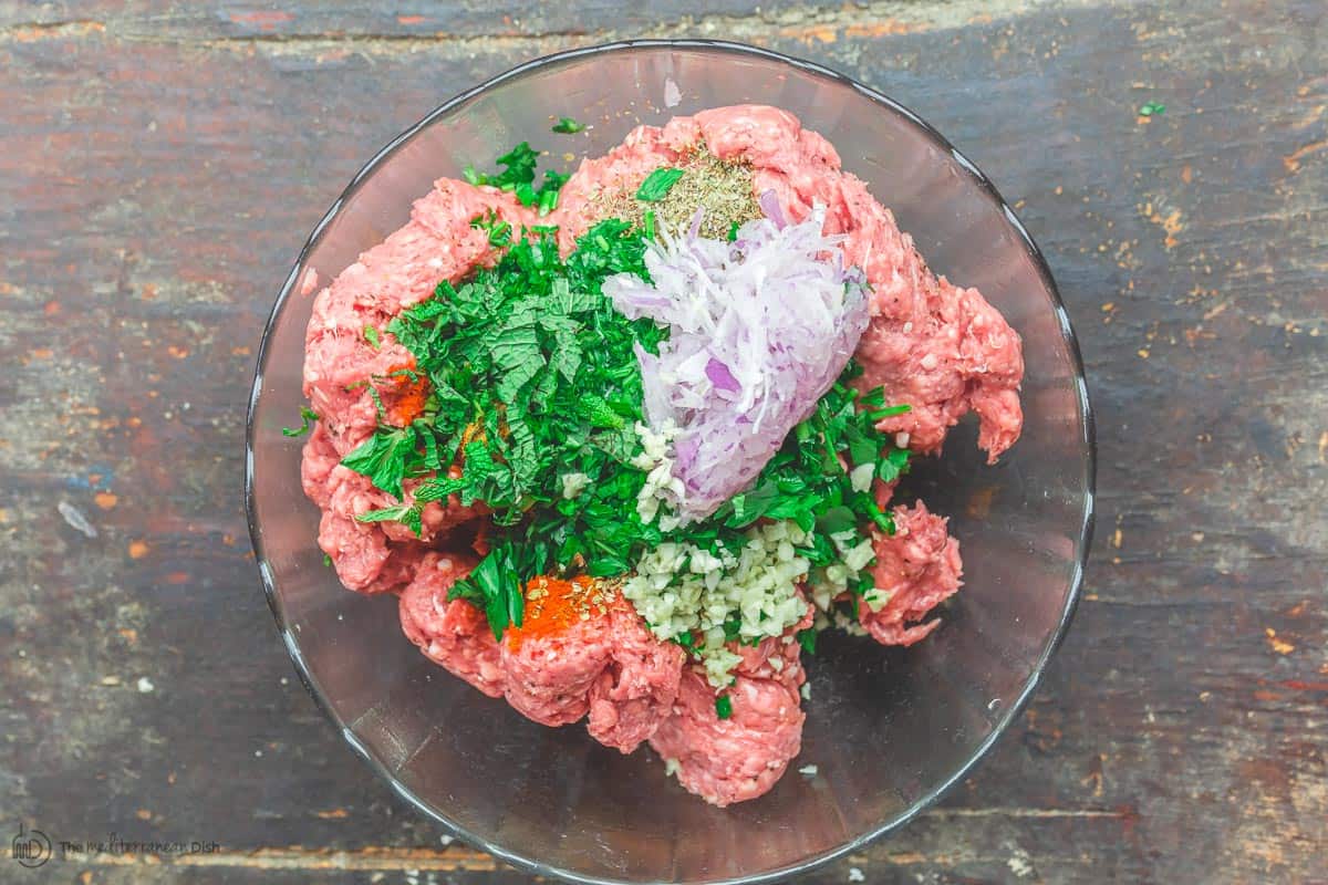 Raw ingredients for lamb burger placed in a mixing bowl