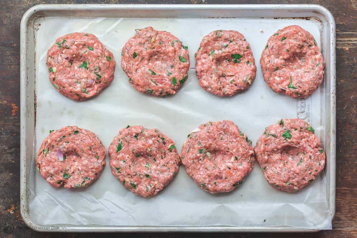 Eight Greek lamb burger patties arranged on a tray
