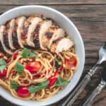 Chicken and spaghetti with tomatoes and basil served in a bowl