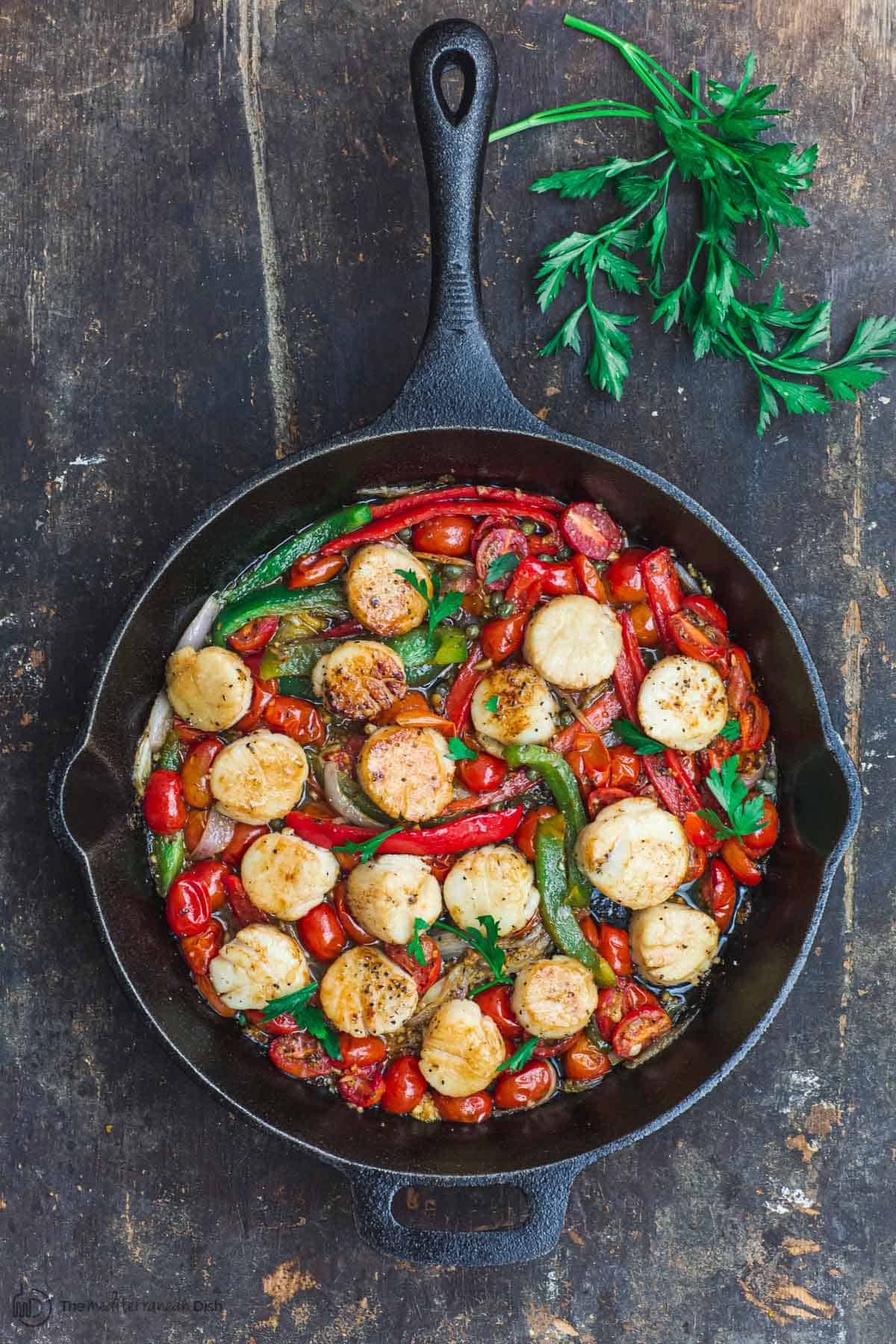 Scallops with tomatoes and bell peppers, sauteed in a cast iron skillet