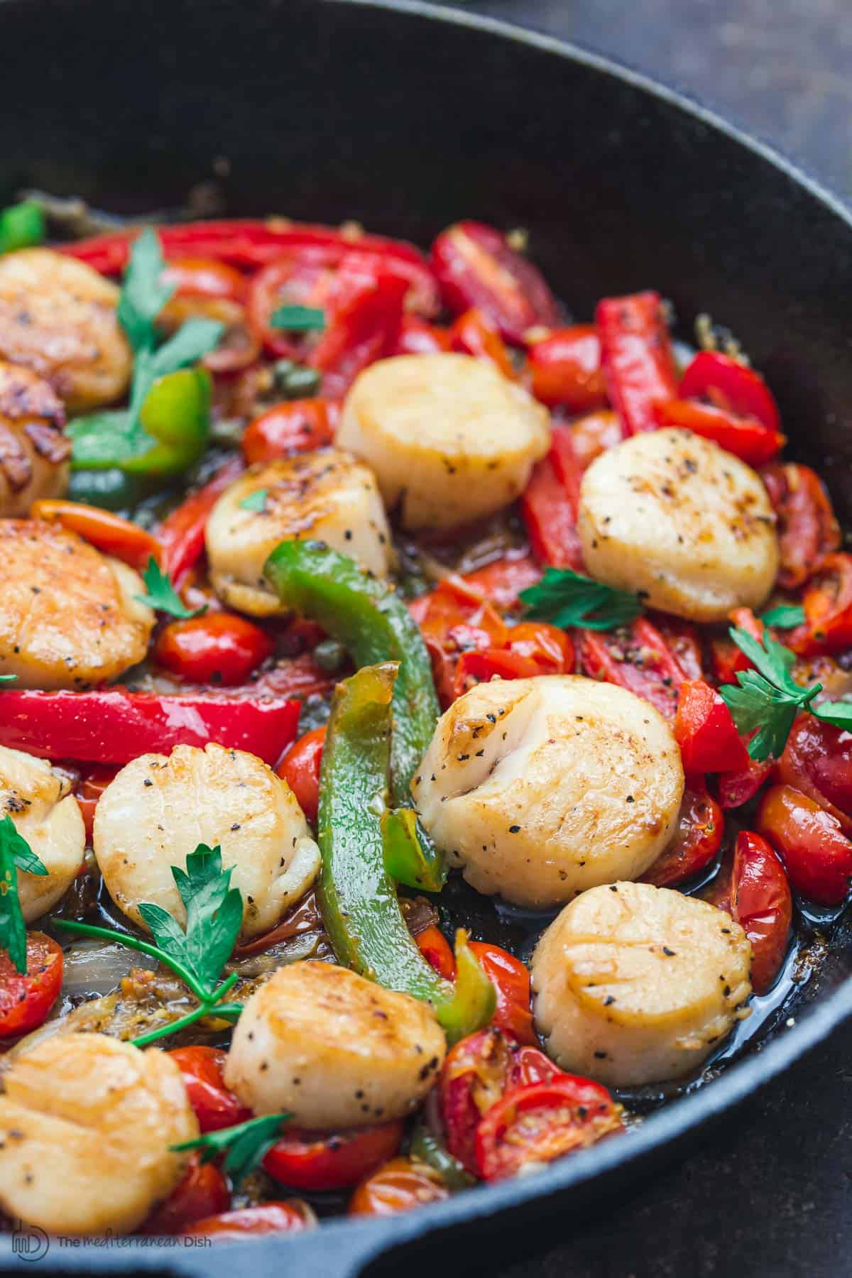 Scallops with vegetables in a cast iron skillet