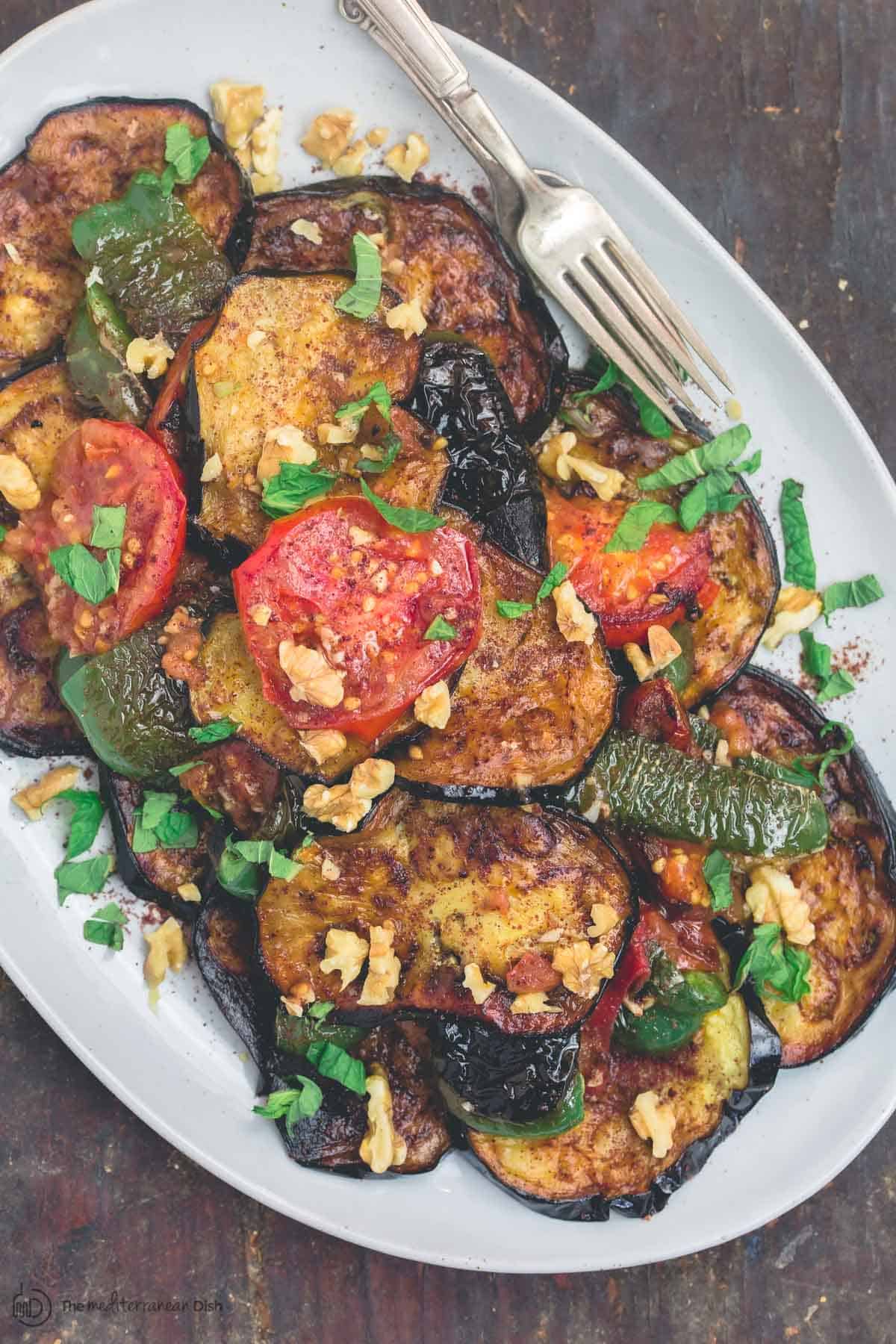 Slices of fried eggplant and vegetables served on a large plate