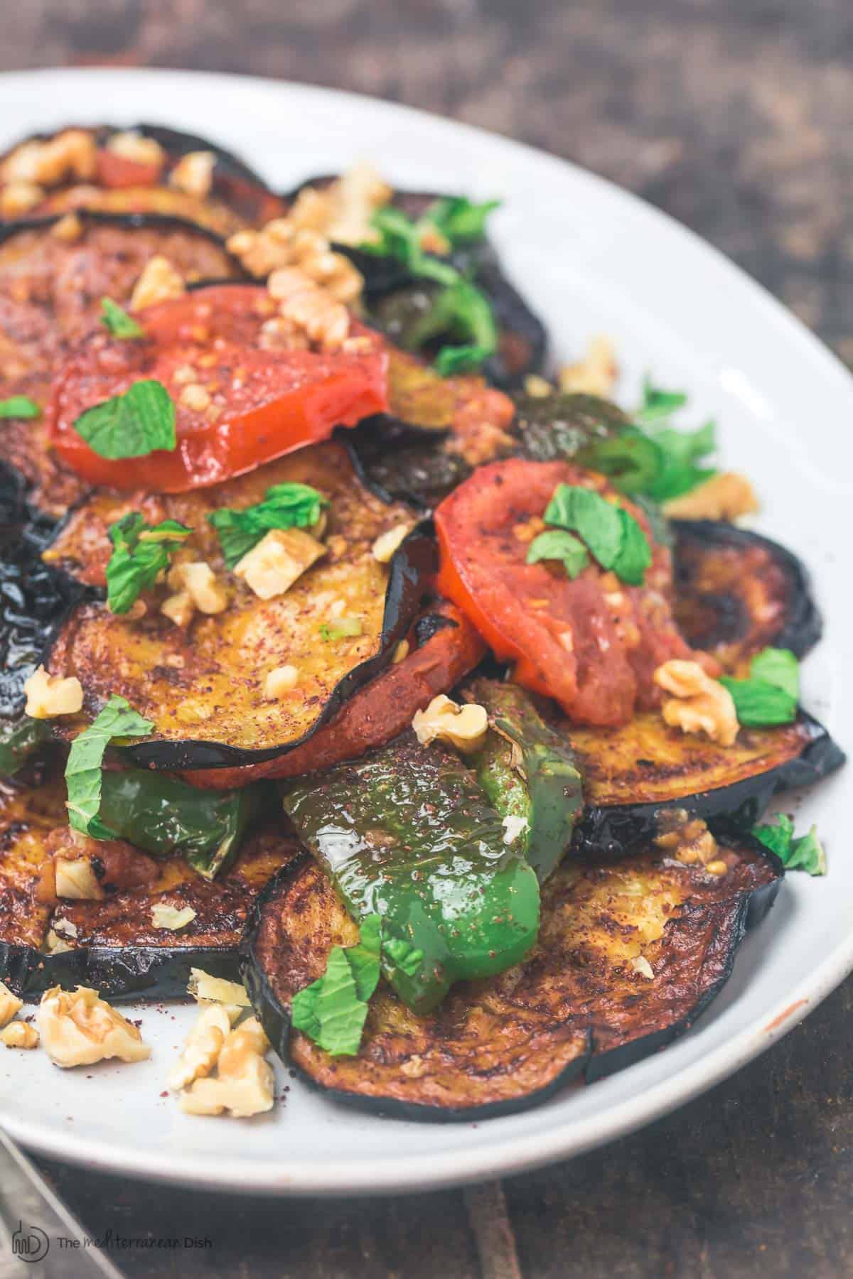 Slices of fried eggplant with mint, tomatoes, green peppers and walnuts