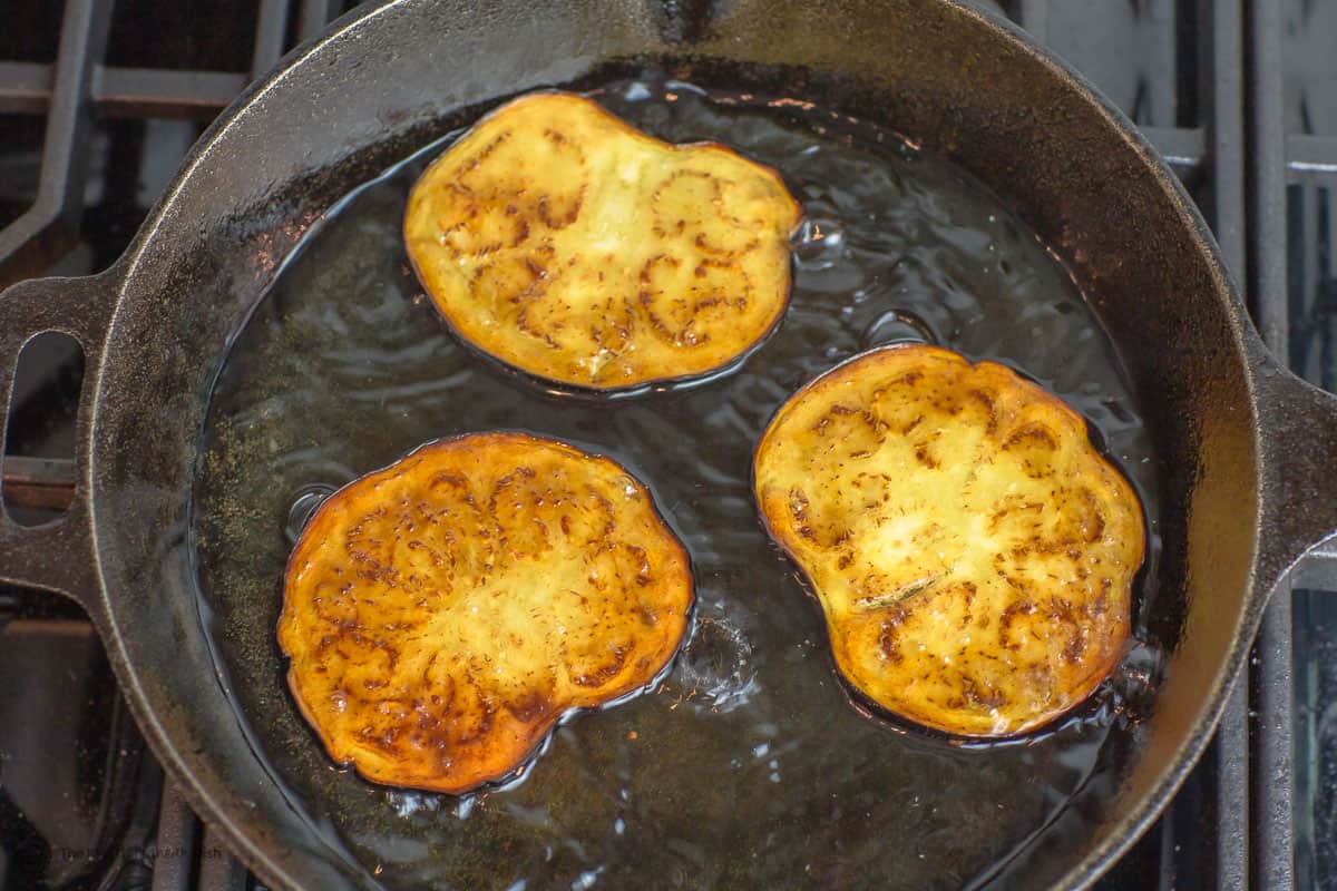 Eggplant slices being fried in a frying pan
