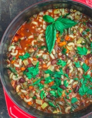 Minestrone soup in a pot with herbs and vegetables.