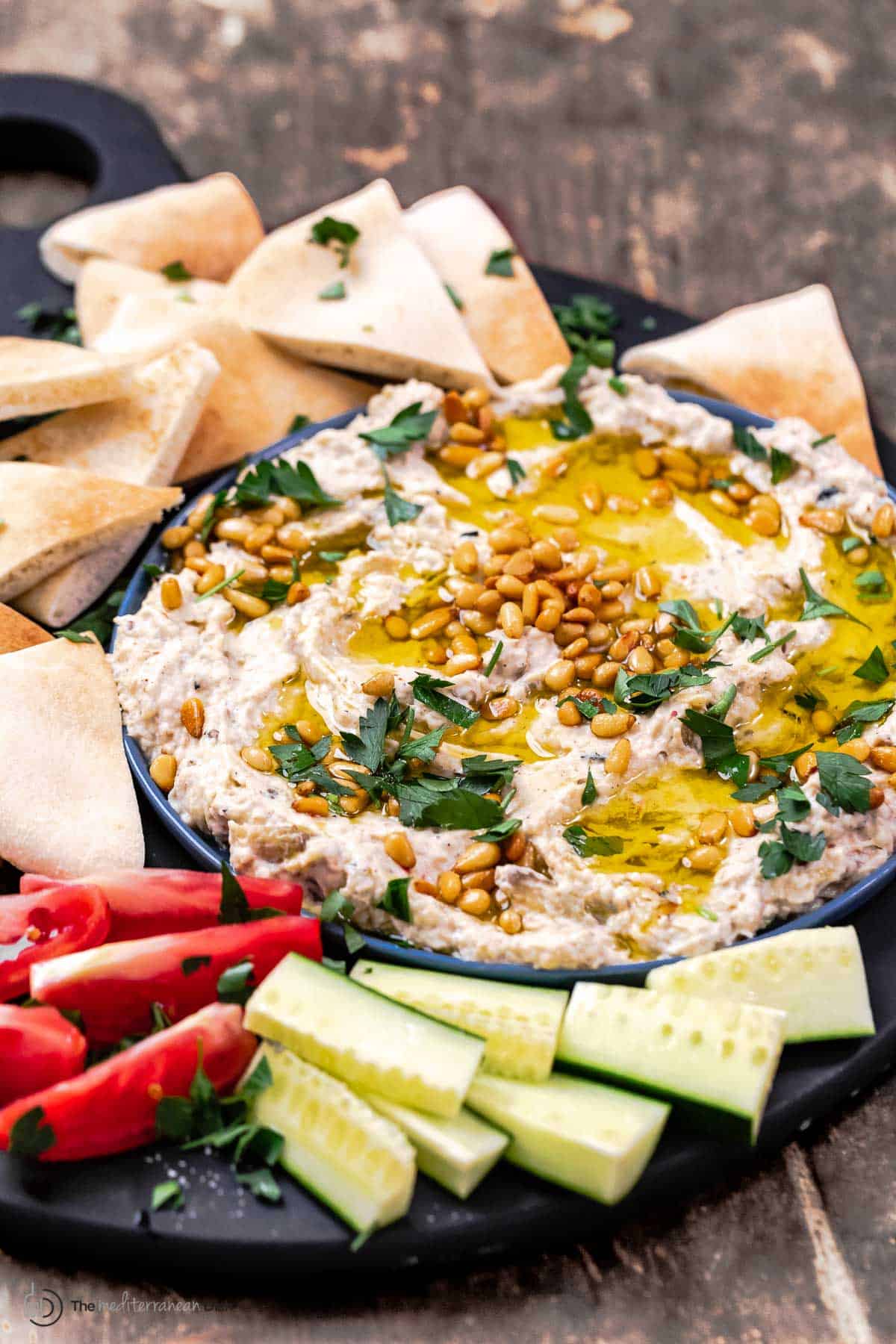baba ganoush eggplant dip on a platter with vegetables and pita wedges