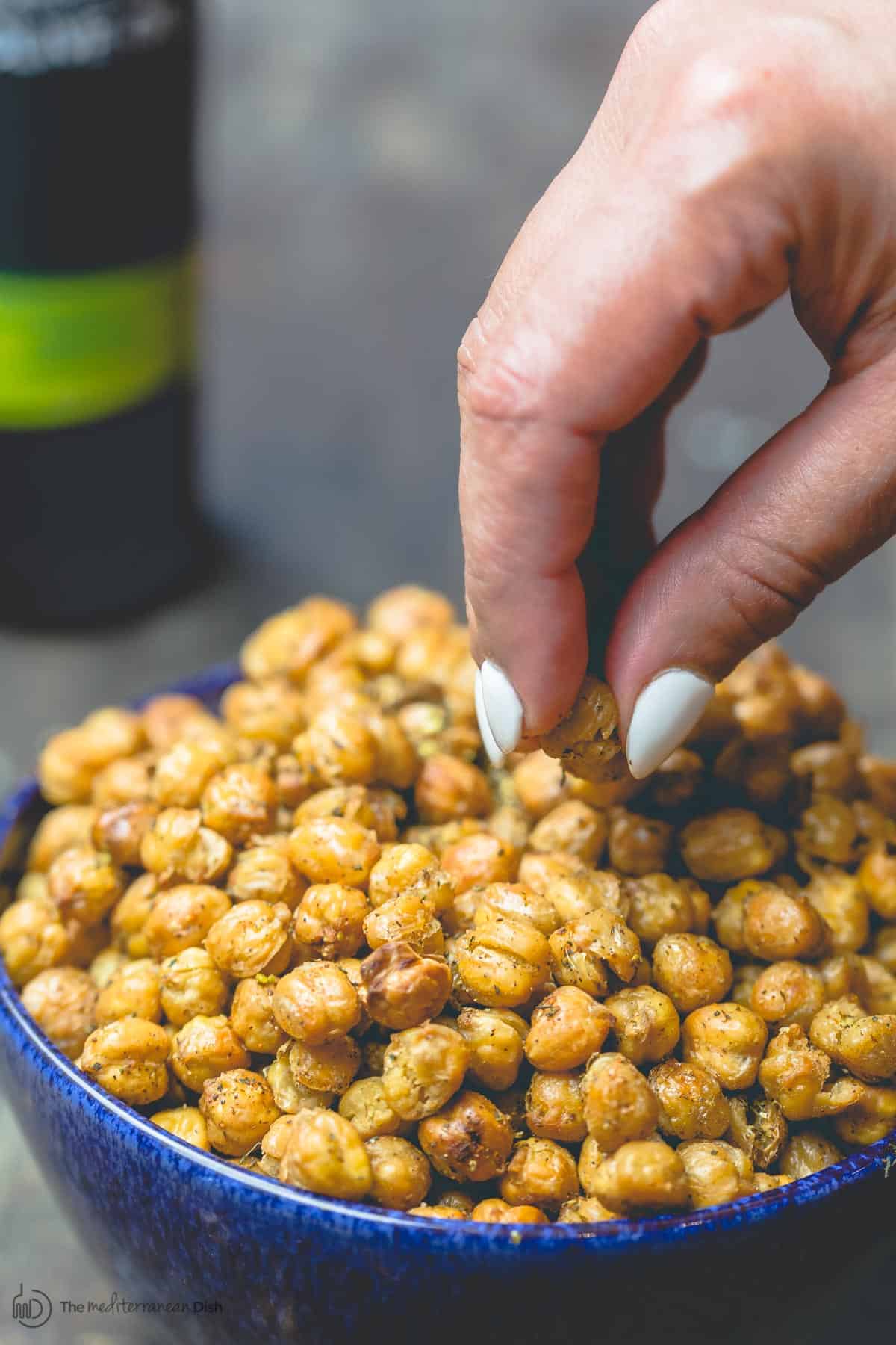 Hand picking roasted chickpeas from bowl