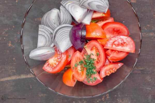 Tomatoes and onions quartered in a mixing bowl