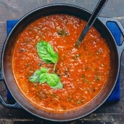 Roasted Tomato Basil Soup in a large pot with ladle. Garnished with basil
