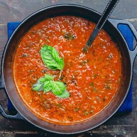 Roasted Tomato Basil Soup in a large pot with ladle. Garnished with basil
