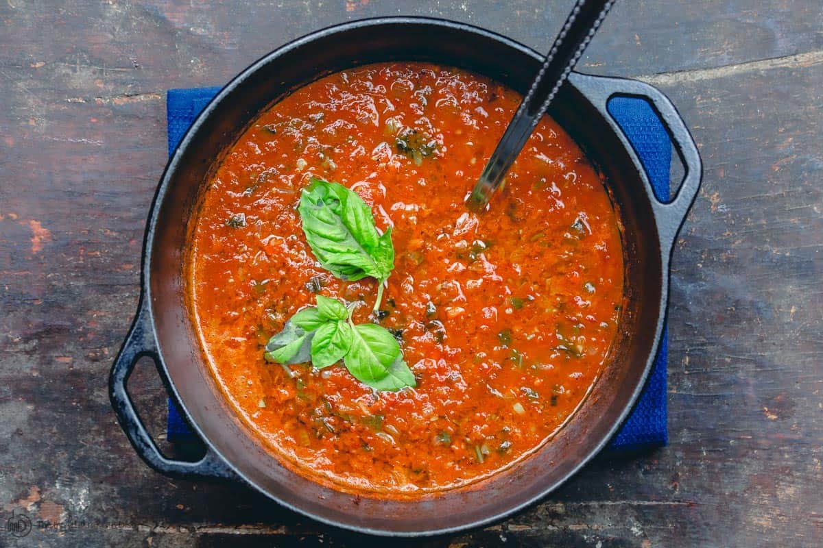 Soupe de tomates rôties et basilic dans une grande casserole avec une louche.  Garni de basilic
