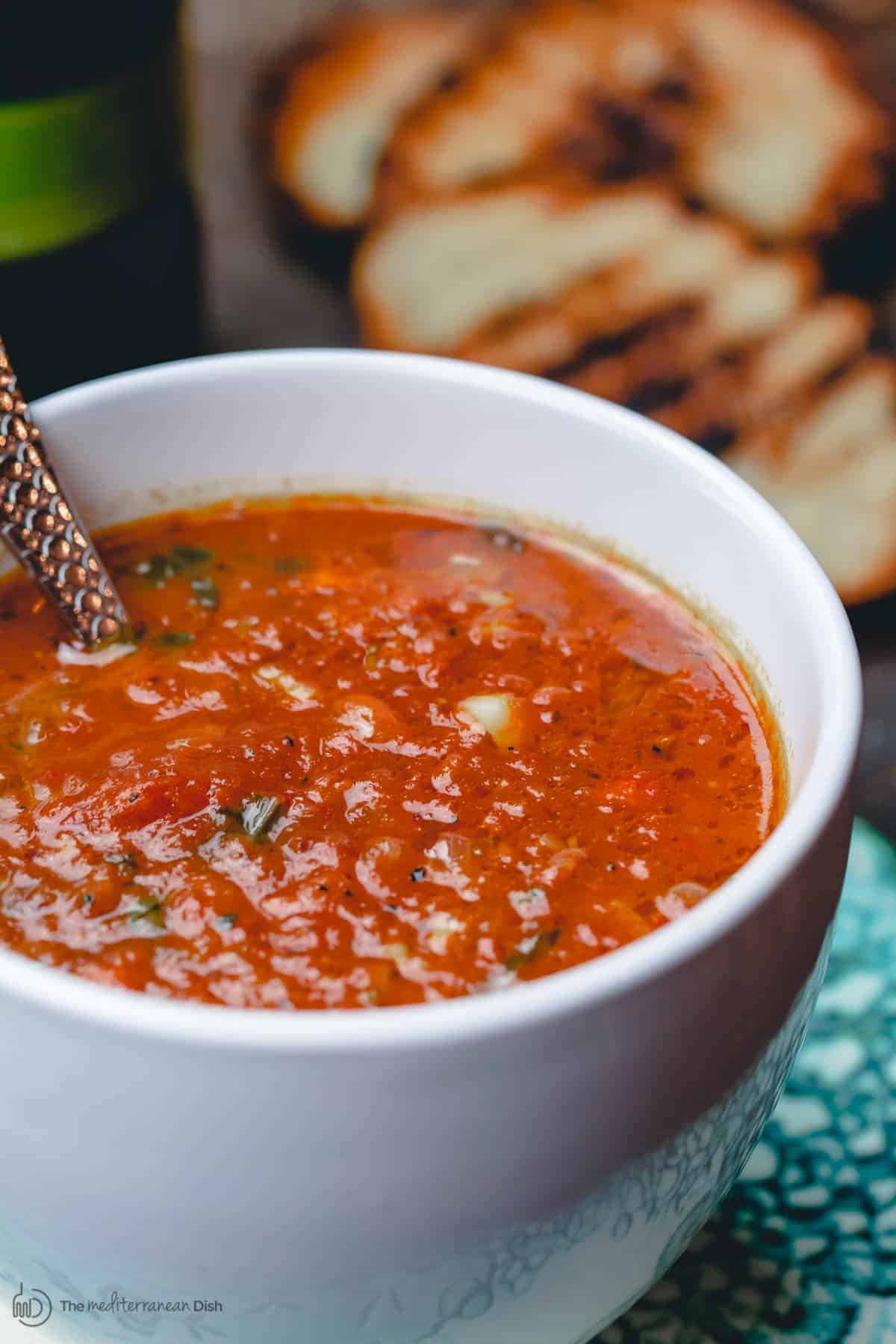 Soupe de tomates rôties et basilic servie dans des tasses avec des tranches de pain grillées
