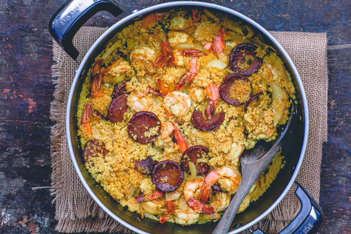 A large pot containing shrimp, spicy couscous and chorizo