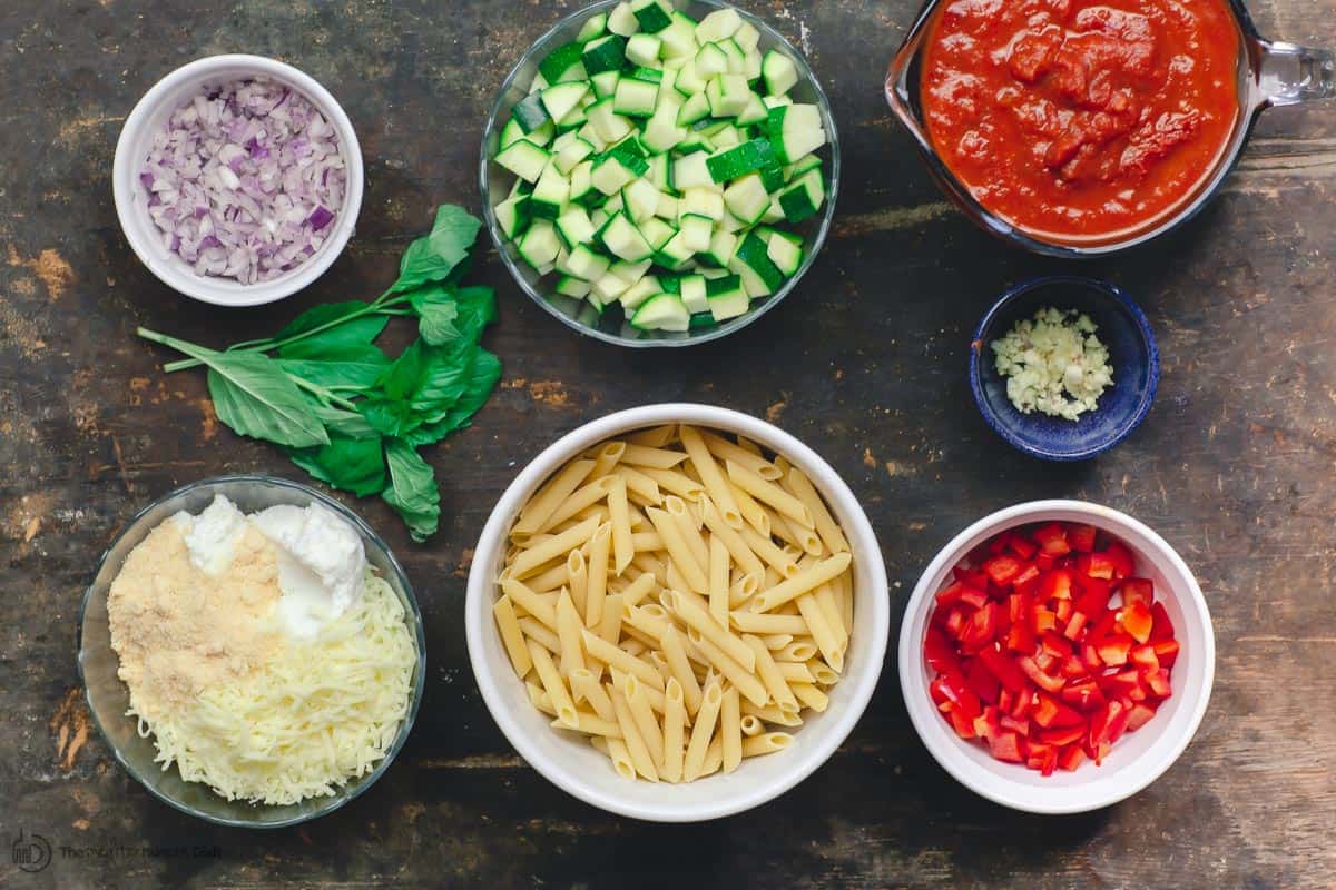 Ingredients for vegetarian baked ziti. Pasta, vegetables, sauce, and ricotta cheese mixture