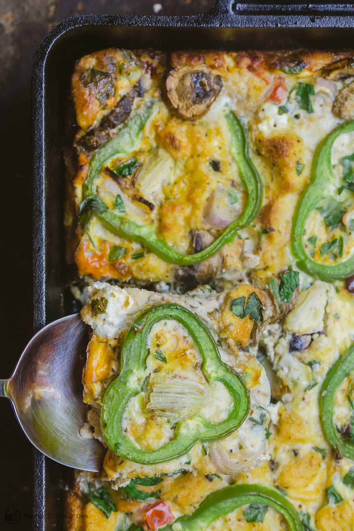 A serving spatula lifting one square of egg casserole