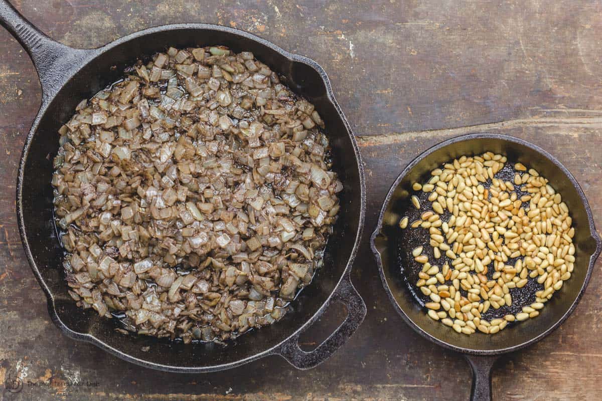 Cooked onions and roasted pine nuts in two skillets