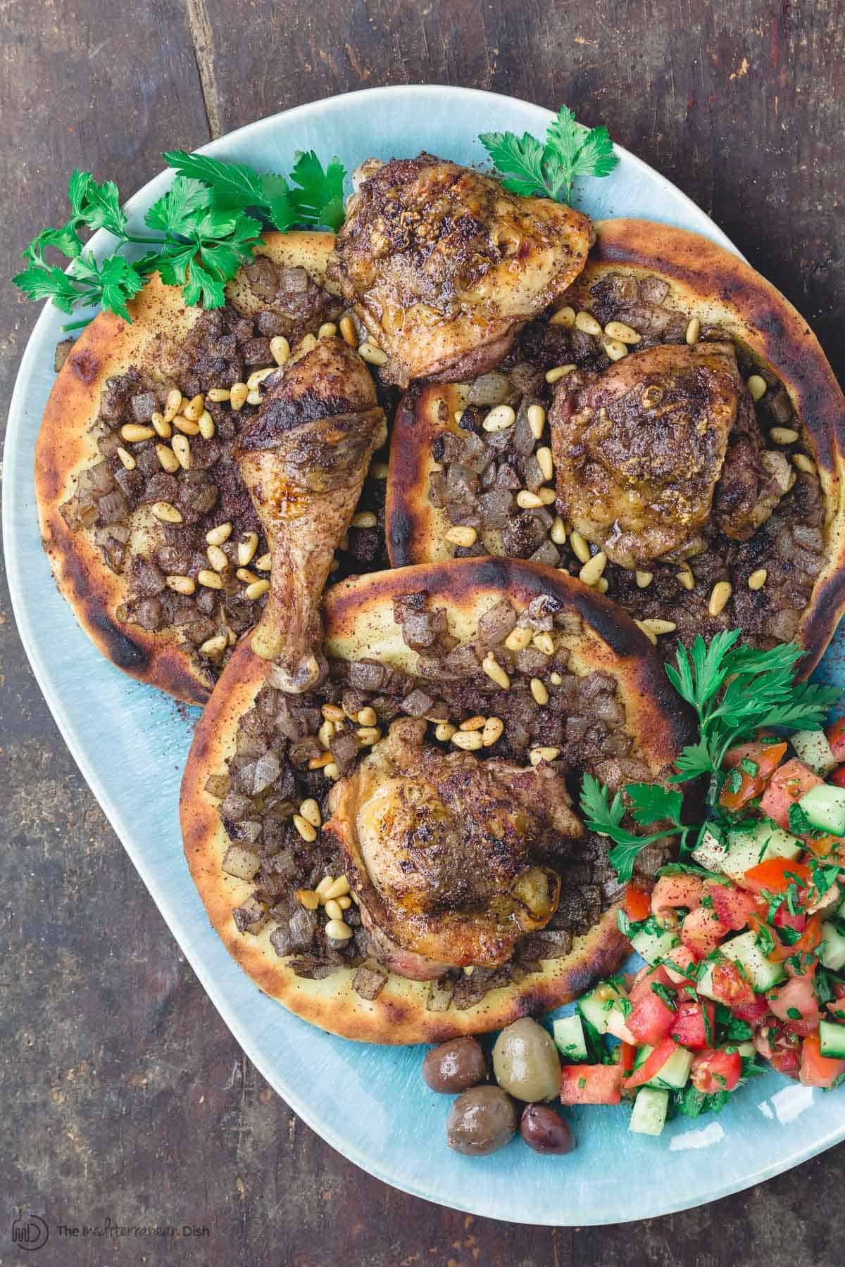 Musakhan sumac chicken over carmalized onion flatbread with side salad