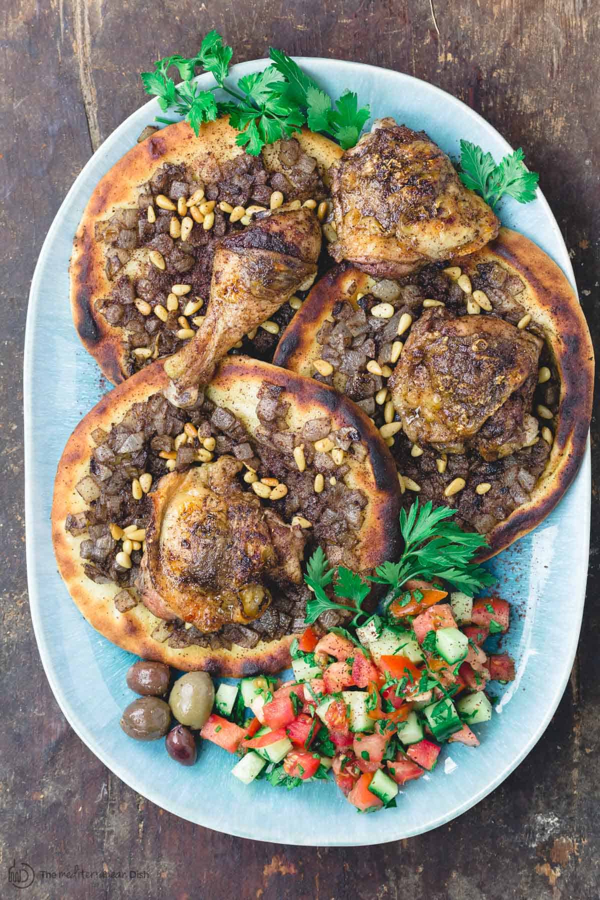 Platter of musakhan chicken with side salad and olives