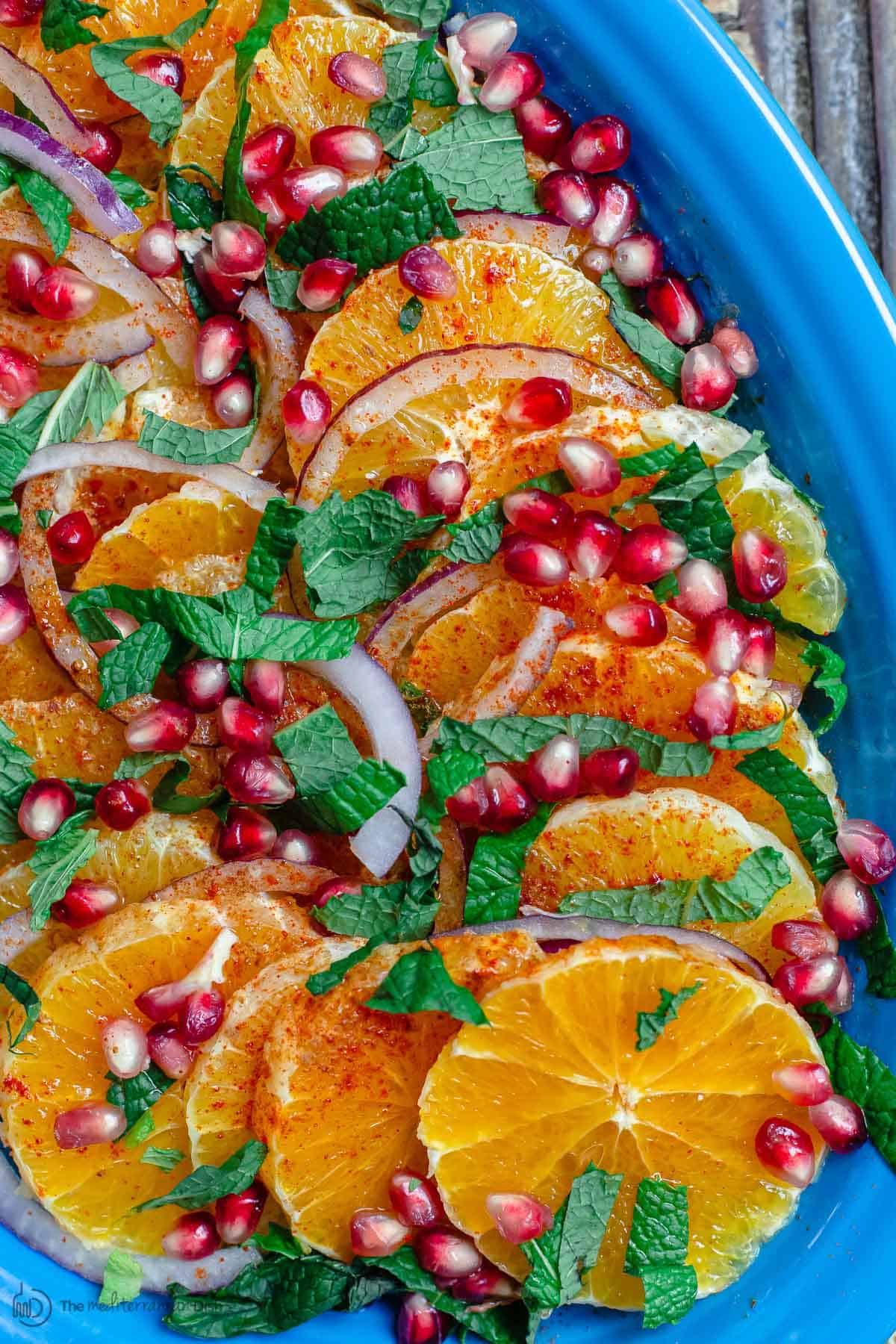 Orange Salad arranged on platter with pomegranate seeds, fresh mint, and onions