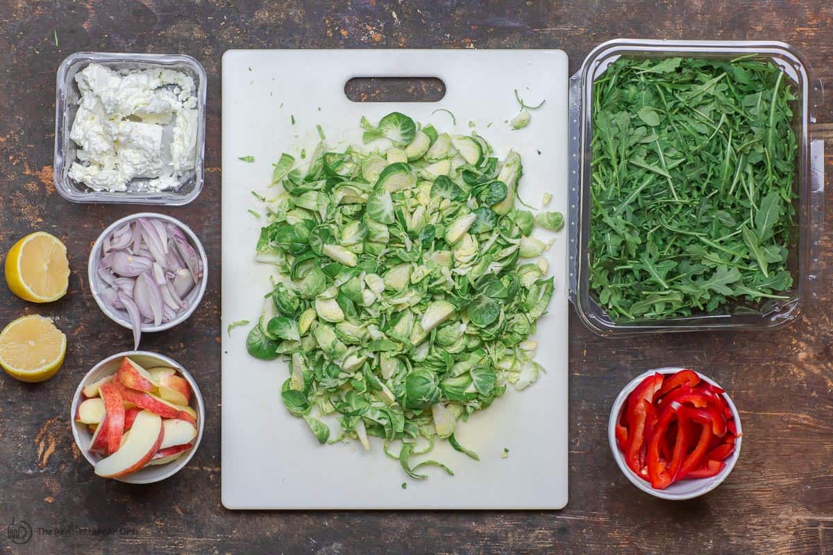 Ingredients for brussels sprouts salad. brussles sprouts, arugula, eppers, apples, shallots, feta and citrus