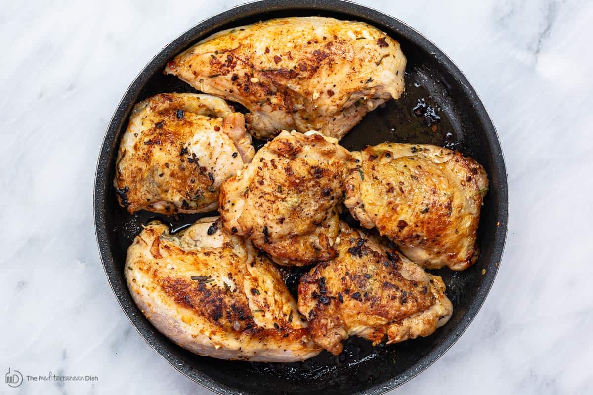 Chicken pieces browned in a pan