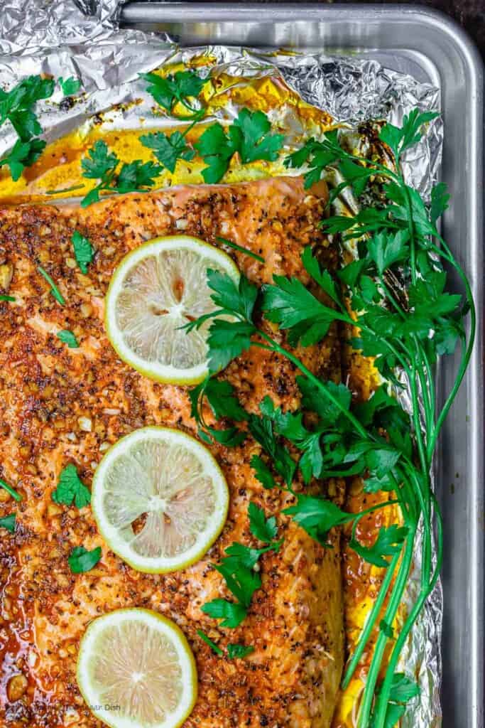 Lemon Garlic Salmon on Baking Sheet with Parsley Garnish and lemon slices