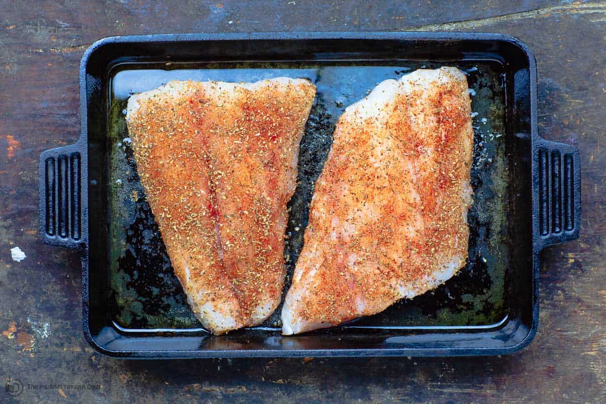 Fish fillets seasoned with spices and placed on baking pan 