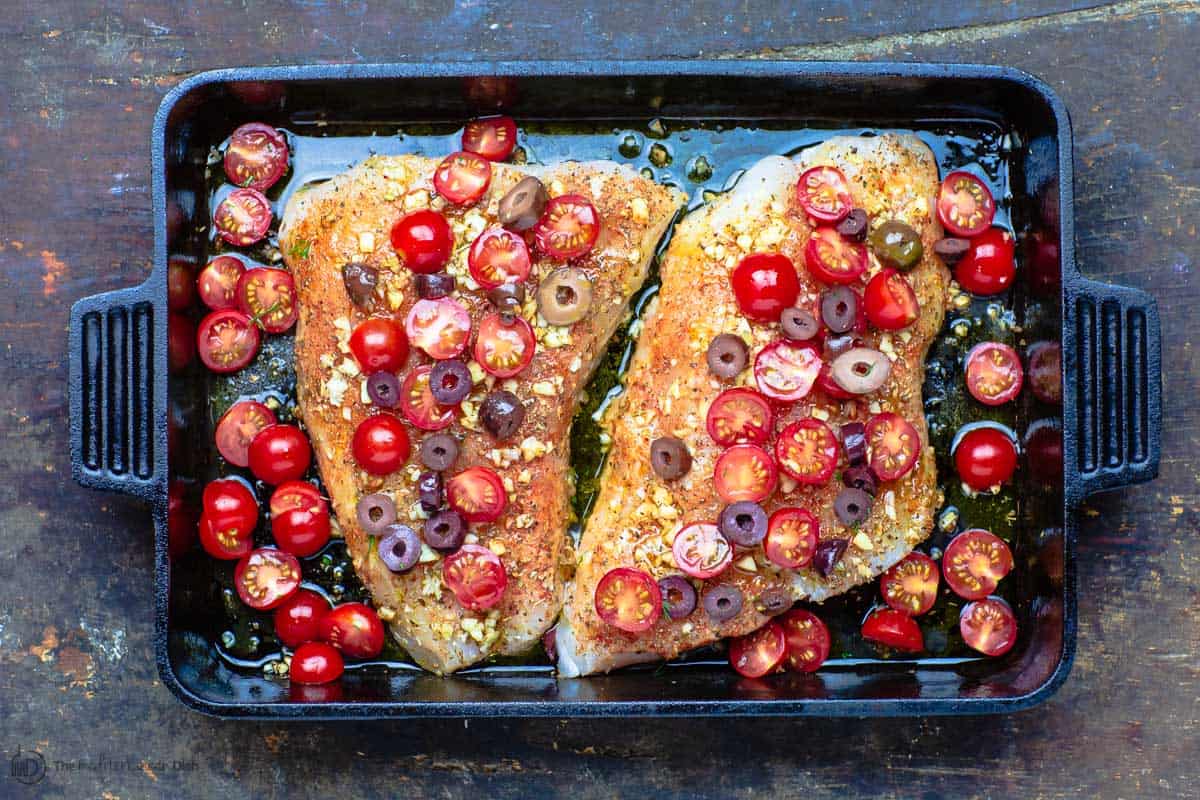 Toppings and olive oil added to the spiced fish