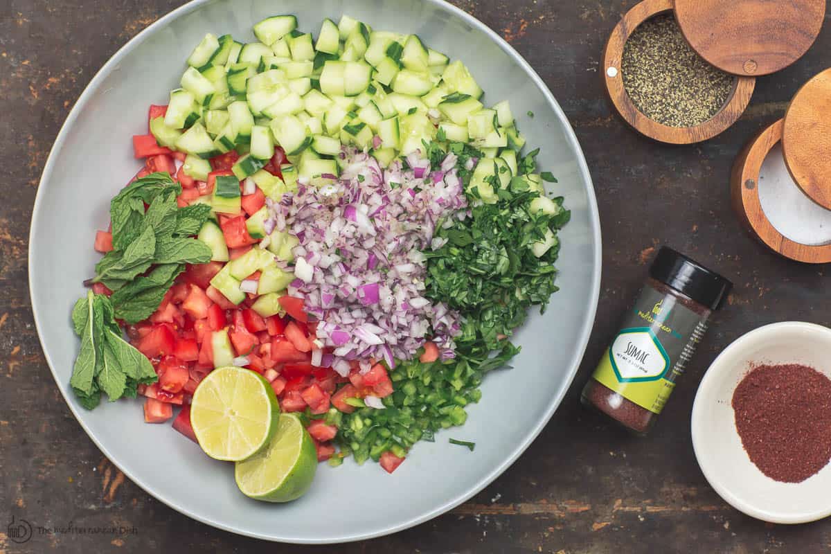 Ingredients for Salade Shirazi. Chopped vegtables, limes, herbs. Spices to the side