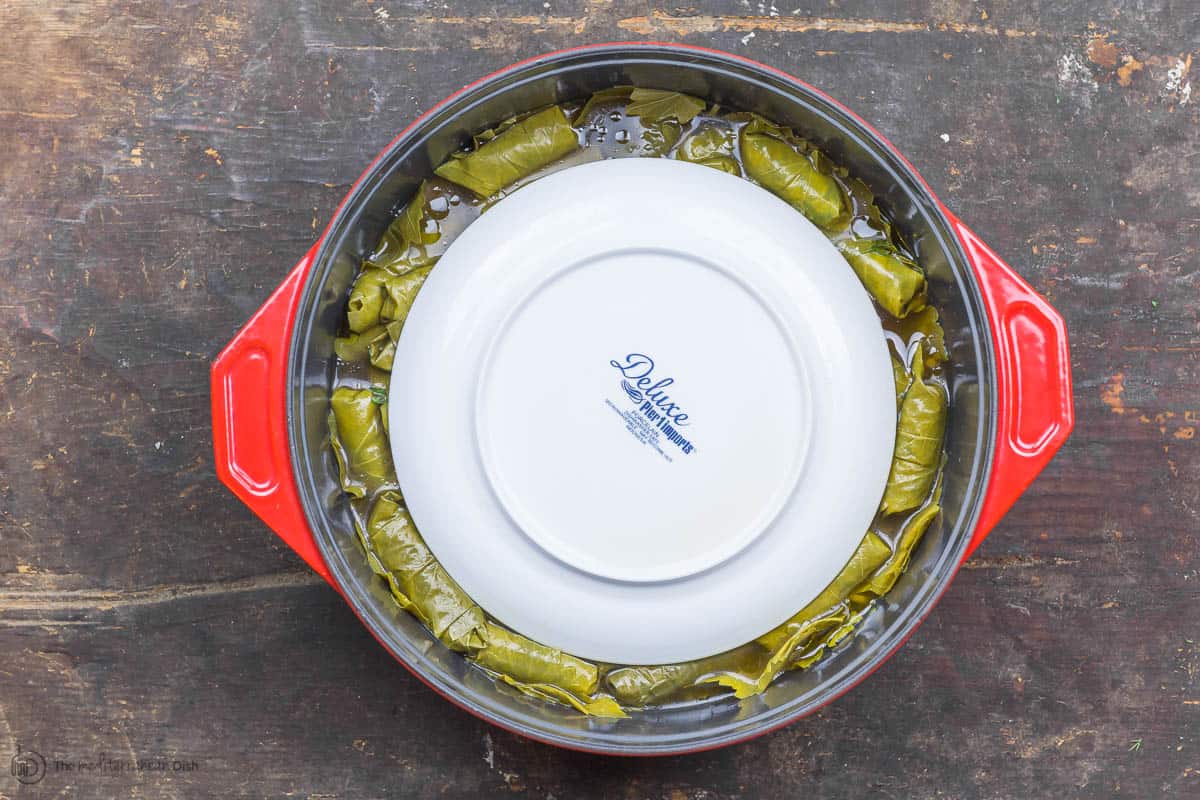 An inverted small plate is added on top of the assembled grape leaves