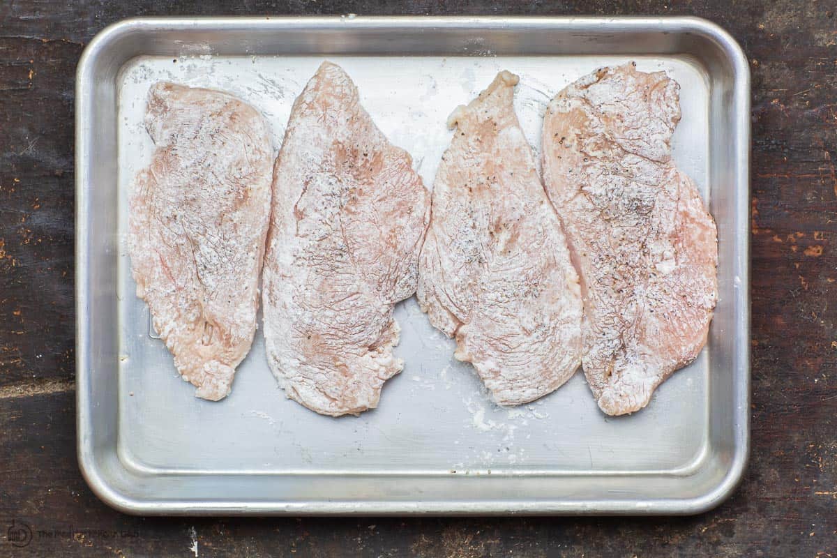 Chicken breast cutlets dredged in flour.